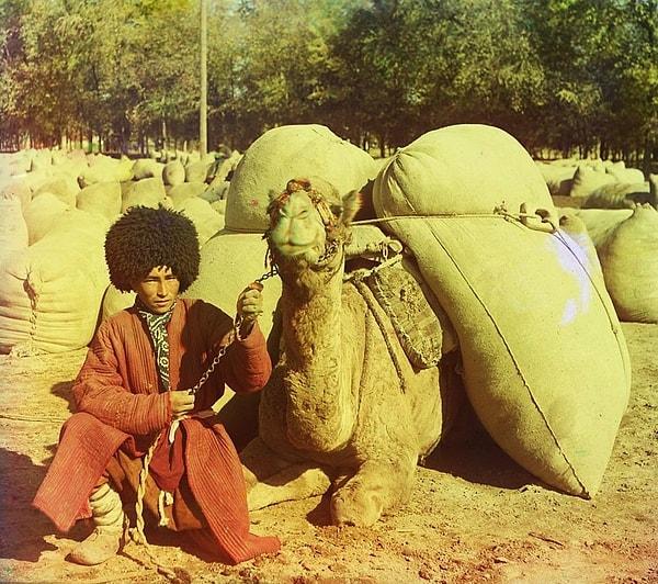 4. Bir adam yüklü develerinin yanında oturuyor.