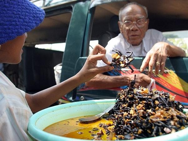 15. Kamboçya’nın Skun şehrinde bir kadın müşterisine kavrulmuş örümcek veriyor. Tith Phalla isimli adam hamburger ve örümceğin farklı tatları olduğunu ancak hamburgerin çok sıradan bir yiyecek olduğunu söylüyor