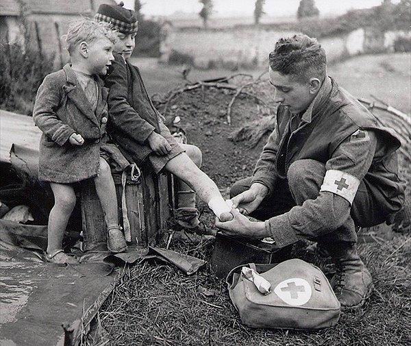 5. II. Dünya Savaşı'nda sıhhiye askeri küçük kardeşinin yanındaki abisinin yaralı ayağına pansuman yapıyor.