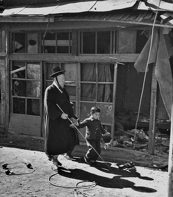 17. Küçük bir çocuk savaşın yakıp yıktığı sokaklarda kör yaşlı adama rehberlik ediyor. (Kore Savaşı, 1951)