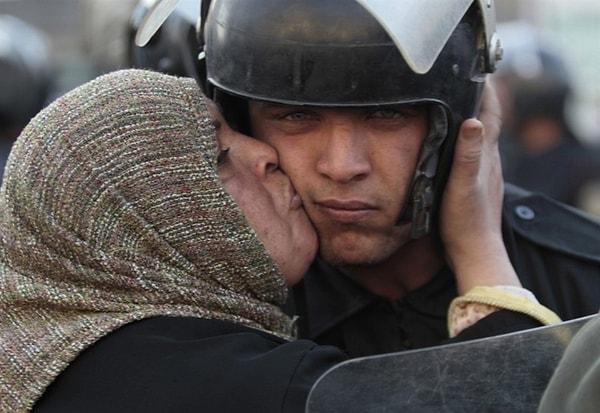 40. Mısırlı bir kadın, olaylarda halka saldırmayı reddeden bir polisi anne şefkatiyle öperken yakalanan bu fotoğraf tarihe geçecek karelerden biri olarak hafızamıza kazınıyor. (2011)