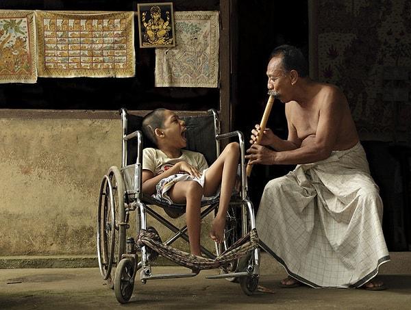 24. Sakat bir çocuk için enstrümanını çalan bir adam, Bali.