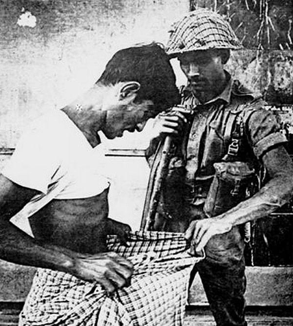 24. Bangladeş Bağımsızlık Savaşı sırasında bir Pakistan askeri, bu adamın Hindu olup olmadığını kontrol ederken, 1970.