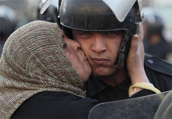 7. Mısırlı bir kadın, göstericilere ateş etmeyi reddeden bir polisi öperken.