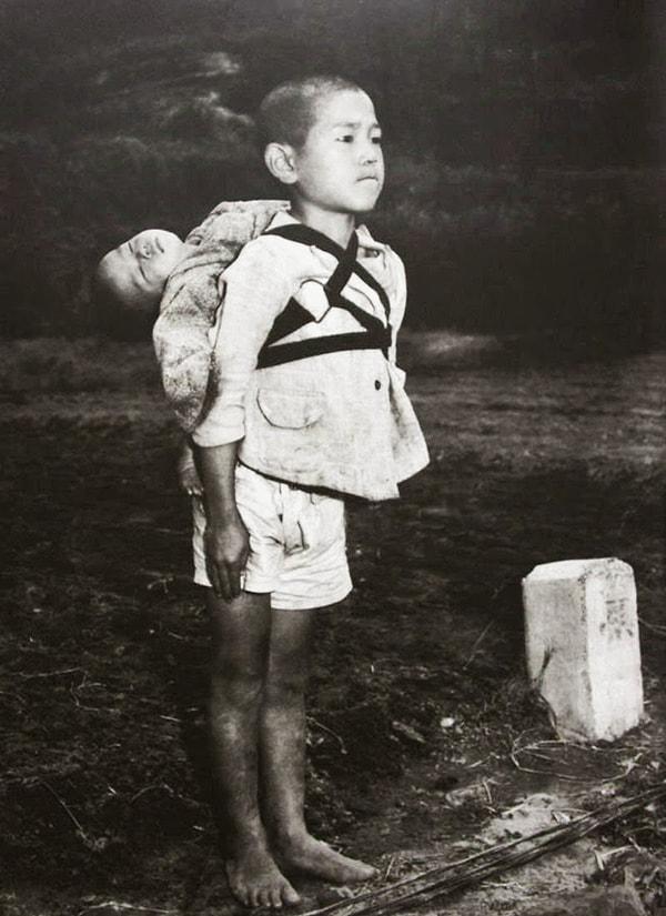 36. Sırtında taşıyarak kardeşinin cansız bedenini yakılması için getiren Japon çocuk hazırolda dikilirken, 1945