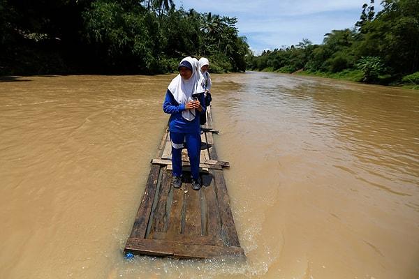 17. Bir kayıkları bile olmadığı için tahtalarla nehri geçmeye çalışan öğrenciler. Cilangkap, Endonezya.