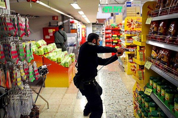 15. İsrailli bir polis memuru, bir kadının Kudüs Otobüs Terminali'nde bıçaklandığını haber alması üzerine, terminaldeki bir süpermarketi ararken.