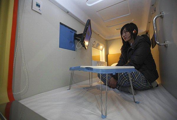6. Çin'in Qingdao kentinde bulunan bir kapsül otelde televizyon izleyen kadın.