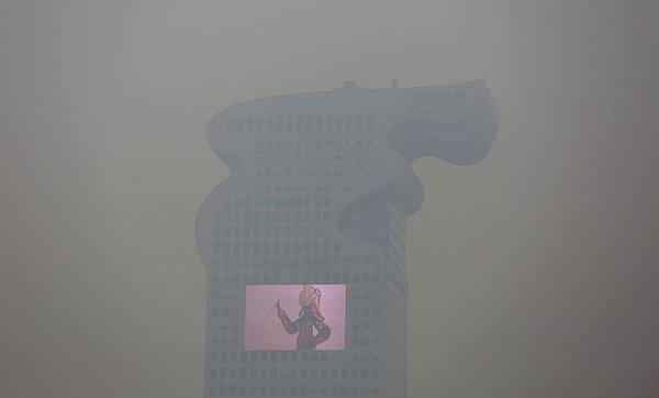 1. Çin'in başkenti Pekin'de hava kirliliği nedeniyle "kırmızı alarm" verildiği sırada, kirli hava tabakasının içinden görülen bina ve büyük ekran. 8 Aralık 2015.