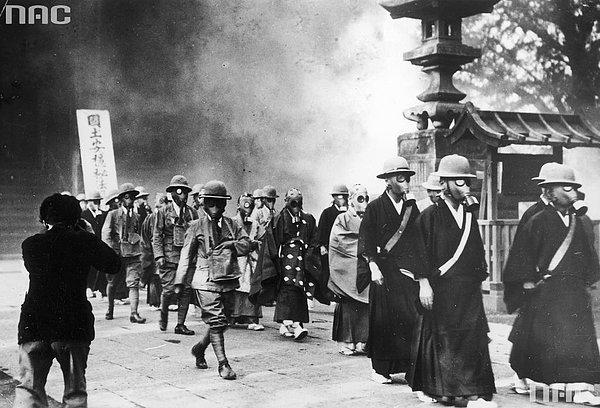 14. Gaz maskeleri takmış birbiri ardına yürüyen Japon sivil ve Budist rahipler, 1936.