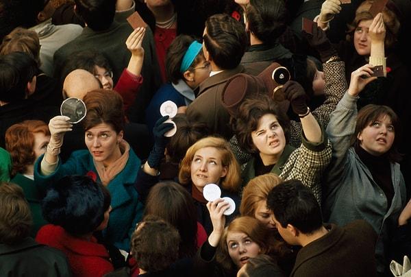 14. Kalabalığın içindeki kadınlar kraliçeyi görebilmek için pudra aynalarını kullanıyor. Londra. Haziran, 1966.