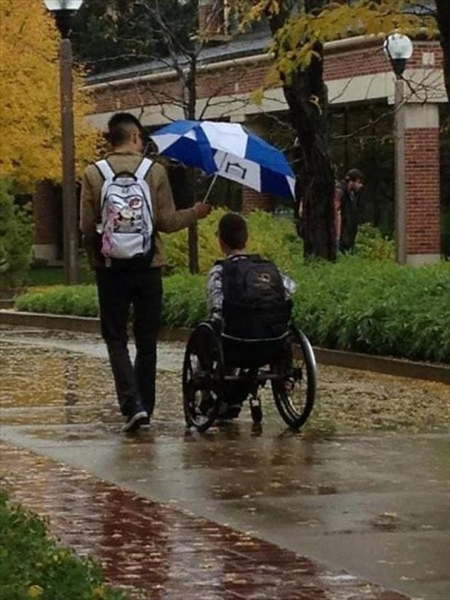 9. This man who walks with this disabled man with his umbrella.