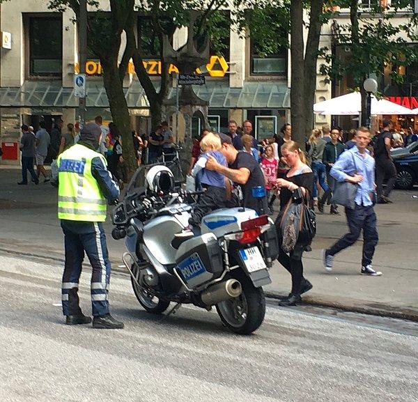 18. Meraklı bir şekilde motosikleti uzaktan inceleyen küçük çocuğu motosikletine bindiren Alman polis.