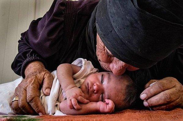 5. Suriyeli bir mülteci, 10 günlük bebeğini güvenli bir şekilde Ürdün'e getirdikten sonra onu öpüyor