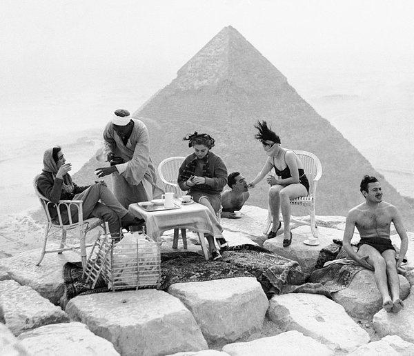 1. Gize'deki dev piramitlere karşı güneşlenen turistler.