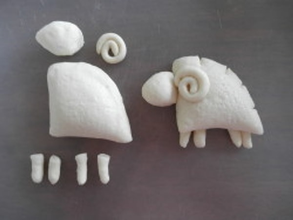 Тонкую часть теста закрутите в рог, толстые разделите пополам — ножки. Прикрепите все части к телу, как показано на рисунке.