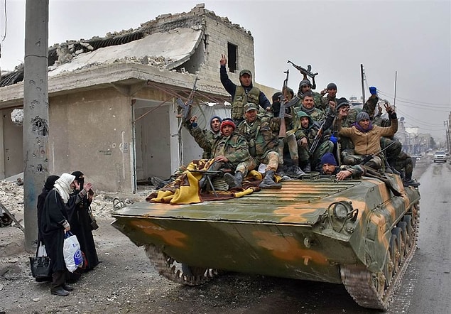 3. Syrian pro-government forces drive past Syrians who fled eastern Aleppo in Masaken Hanano, a former rebel-held district which was retaken by regime forces last week, on Nov. 30.