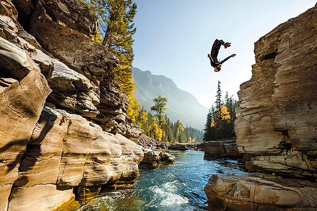 Человек прыгает со скалы в воду. Глейшер (национальный парк, США)