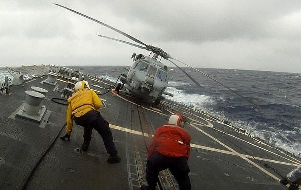 Fırtınaya aldırmadan uçak taşıyıcısı üzerinde çalışan denizciler