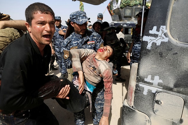 9. Iraqi Federal Police carry a civilian who was injured while opening a booby-trapped shop in Tayaran district, as Iraqi forces battle with ISIS fighters in western Mosul on March 12.