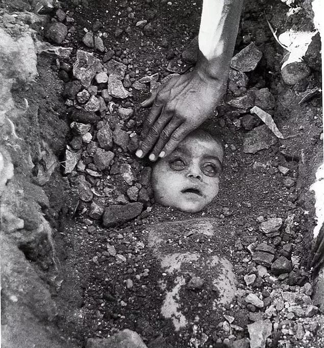 18. Bhopal in 1984, the father burying his daughter who lost her life in a gas disaster.