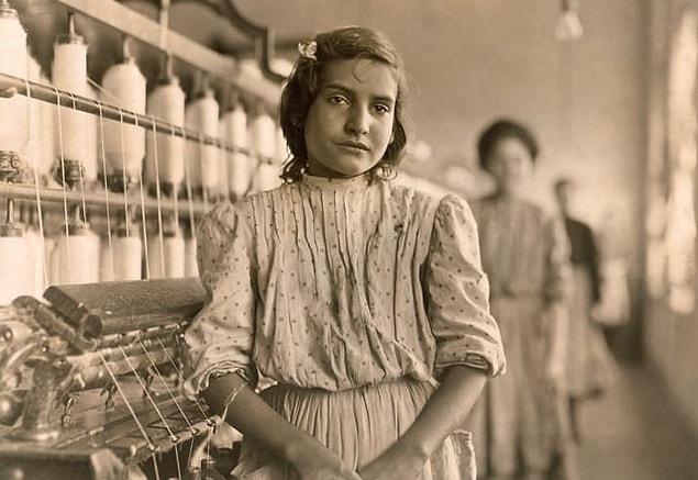 13. A teenage girl pauses from work as a spinner at a cotton mill in Lancaster, South Carolina, circa 1908.