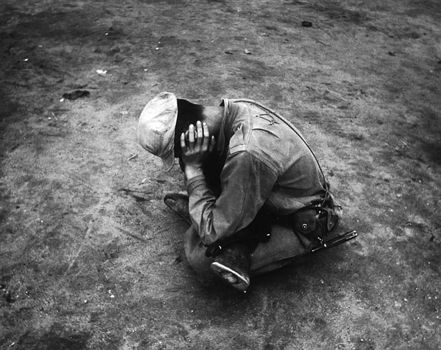 8. A weary and dispirited survivor of a lost battalion sits in despair in 1950.