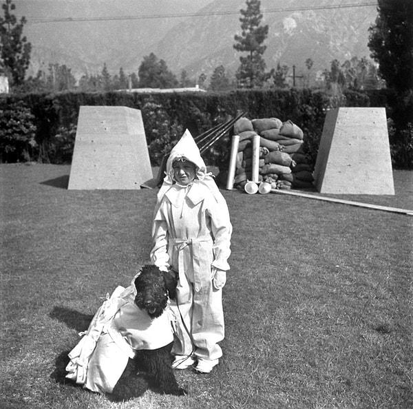15. Sığınaklarının önünde, en yeni atomik korunma kıyafetlerini deneyen çocuk ve köpeği.