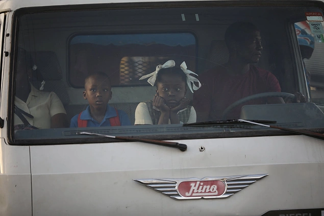 В столице Гаити - Порт-о-Пренсе - детей в школу возят на грузовиках, причём сидят малыши в кабине водителя.