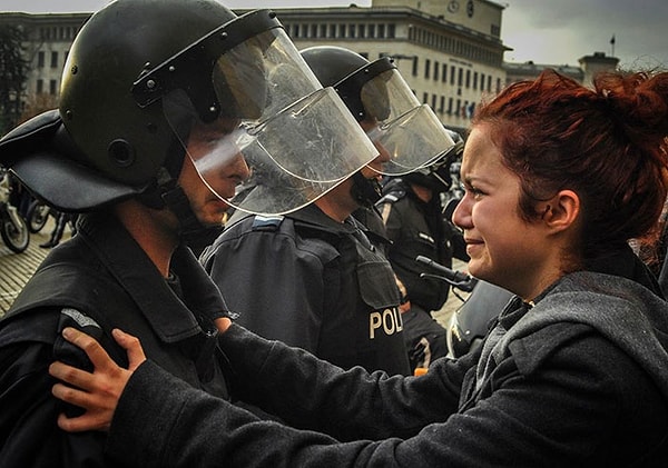 8. Bulgaristan'da bir kadın, protestoculara karşı şiddet kullanmamaları için polis memurlarına yalvarıyor.