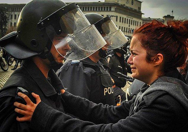 8. Bulgaristan'da bir kadın, protestoculara karşı şiddet kullanmamaları için polis memurlarına yalvarıyor.