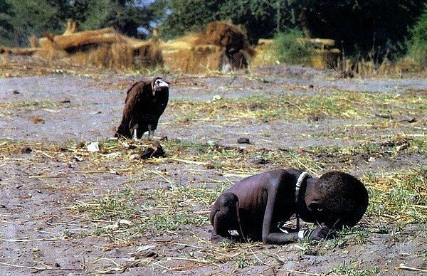 4. Güney Sudan'da açlıktan ölmek üzere kampa ulaşmaya çalışan ve yakınında yırtıcı kuş bekleyen kız çocuğu