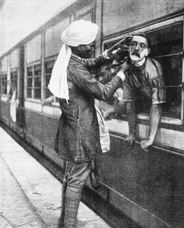 8. Парикмахер-индус бреет британского офицера через окно поезда (1908 год).