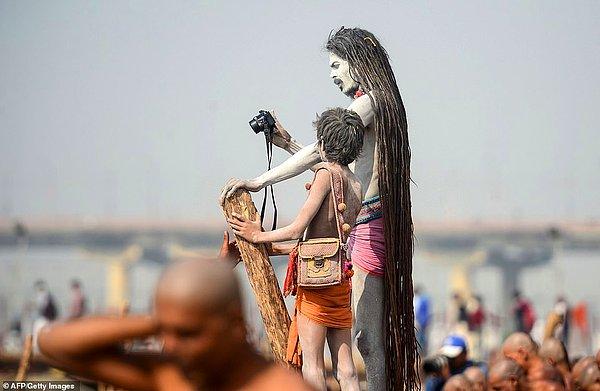 Bir Naga Sadhus, üyeliğe yeni kabul edilen Naga Sadhuslar Ganj Nehri'nde ritüeller gerçekleştirirken fotoğraflarını çekiyor.