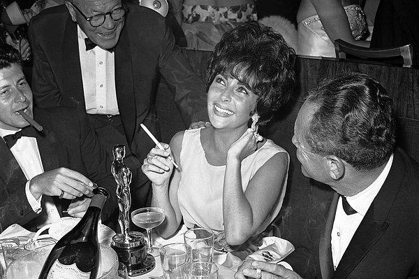 12. Önünde duran Oscar ile Elizabeth Taylor, 18 Nisan 1961 tarihli Akademi Ödülleri'nden sonra bir partide kendini rahatlatıyor.