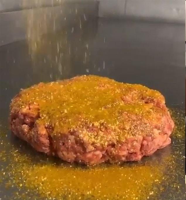 Nusret videoda, hamburger köftesini ve hatta içine koyacağı peyniri bile altın tozuna bulayarak pişiriyor!