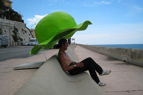 22. Denizin kenarındaki banklarda oturan insanları güneşten korumak için yapılmış devasa şapka...