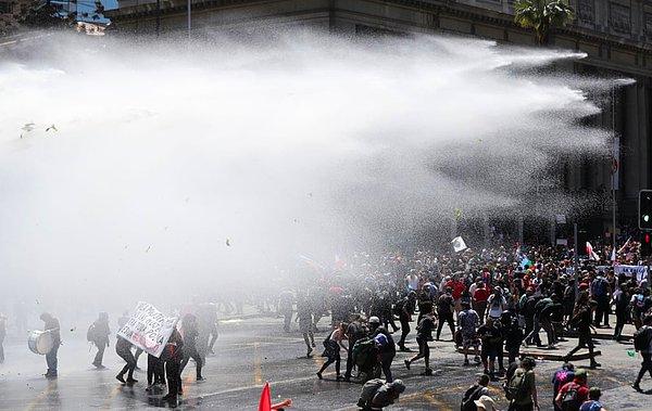 Göstericiler, tazyikli su kullanan güvenlik güçleri tarafından püskürtüldikten sonra kaçıyor...