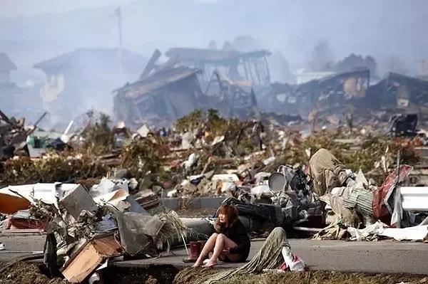 9. 2011 yılında Japonya'da yaşanan korkunç deprem ve tsunaminin ardından bir kadın evinin yıkıntısı önünde oturuyor.