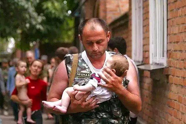 3. Çeçenistan yakınlarındaki Kuzey Ossentia'da 2004 yılında silahlı insanların bir okulu rehin almasının ardından bir Rus polisi salınan bebeği taşıyor.