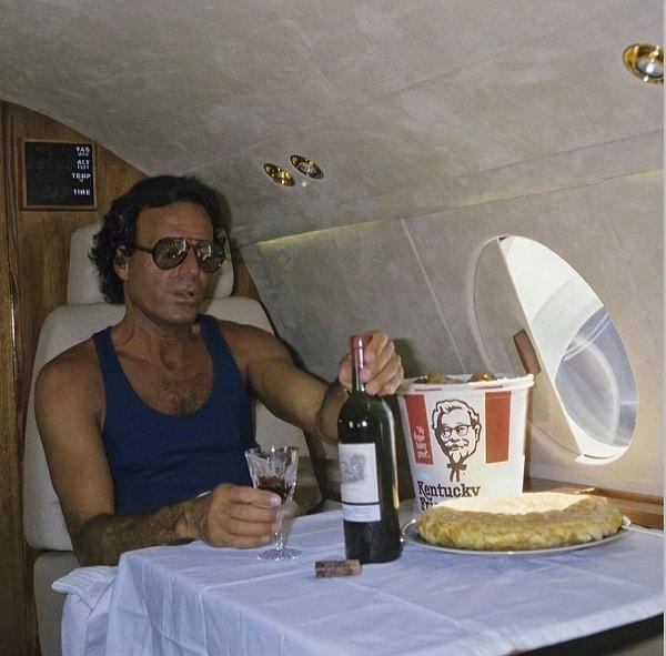 24. Julio Iglesias 1986 yılında özel jetinde kırmızı şarap içip, KFC yerken.