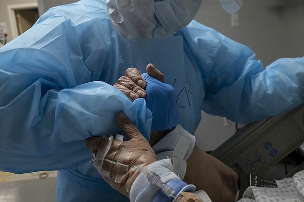 4. "31 Ekim, Houston'da bir sağlık çalışanı koronavirüs yoğun bakım ünitesindeki bir hastanın yatakta yer değiştirmesine yardımcı olmak için elini tutarken."