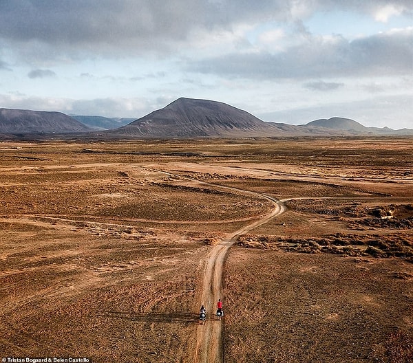 Снимок с дрона Тристана и Белен на велосипеде по Лансароте. В книге говорится: «Благодаря вулканическим образованиям, которые варьируются от темно-красного до темно-черного, и сухим коричневым трещинам, можно пройти через чудесный спектр цветов».