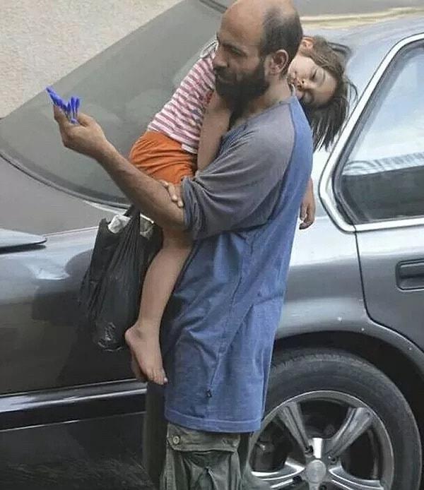 1. Suriyeli mülteci olan Abdu, kızını kucağında tutarak kalem satıyor...