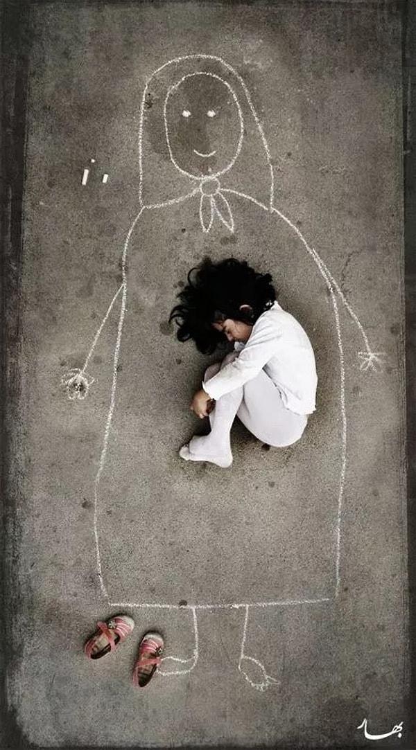 8. Irak'taki bir yetimhanede yaşayan küçük bir kız çocuğu yere anne resmi çizerek üzerinde yatıyor.