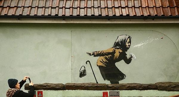 Kimliği belirlenemeyen sanatçı, İngiltere'nin Bristol kentinde bir evin duvarına hapşırırken takma dişleri ağzından fırlayan bir kadın çizdi.