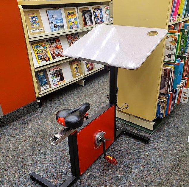 19. "Kütüphanedeki bu çalışma masasında, çalışırken egzersiz yapabilmeniz için bir bisiklet koltuğu ve pedallar bulunuyor.".