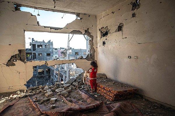 8. Fatima Shbair'dan yıkılmış evinin içerisinden dışarıya bakan Filistinli bir çocuğun görüntüsü.