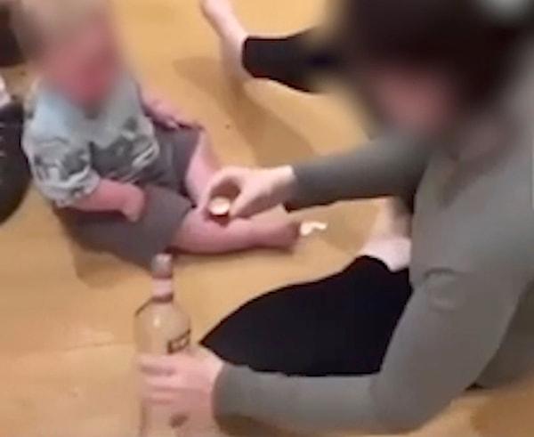 O videoda, annesi olduğu belirtilen bir kadın, yerde oturan çocuğa içinde votka olduğu tahmin edilen şişeden bir şeyler içiriyor.