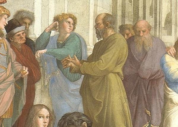 Bir diğer Antik Yunan filozofu, çarpıcı yüz hatlarıyla dikkat çeken Sokrates. Platon'un sol tarafında yer alan Sokrates'in sağ elinin başparmağı ile sol işaret parmağını tutarak öğrencilerine ders verdiği görülüyor.